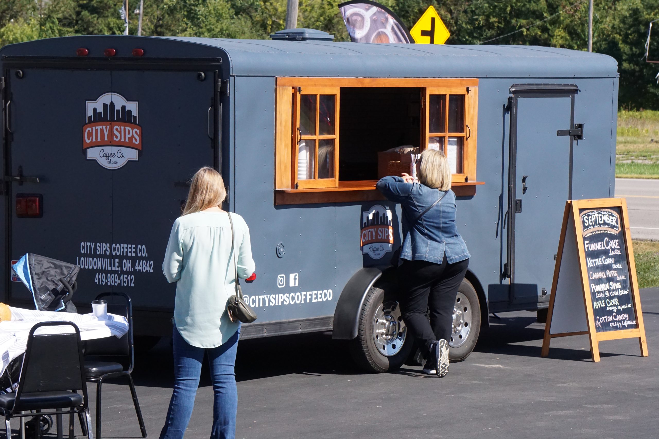 Gray coffee trailer parked in parking lot.