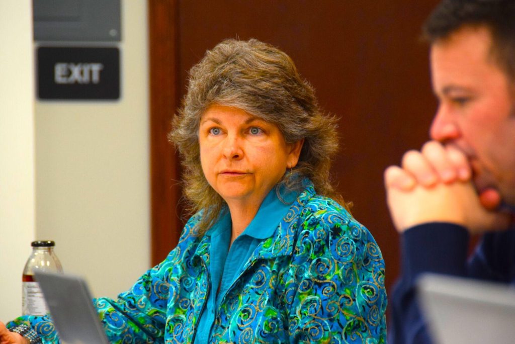 Jean Taddie speaks wearing a blue shirt and teal patterned blazer.