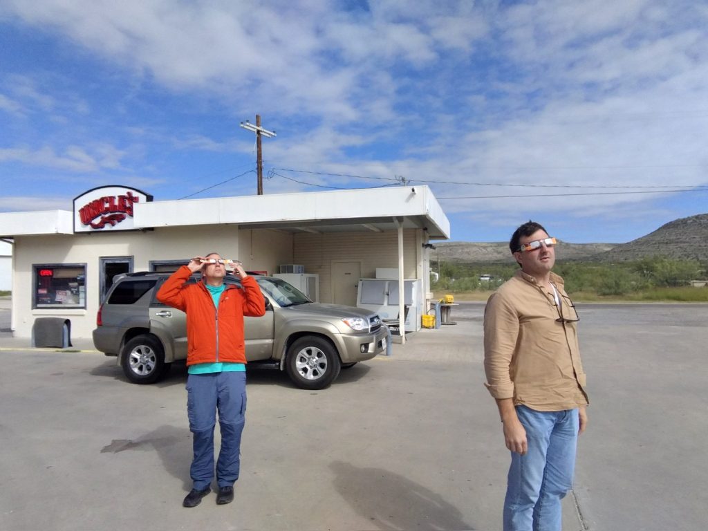 Two humans stare at a solar eclipse with glasses on