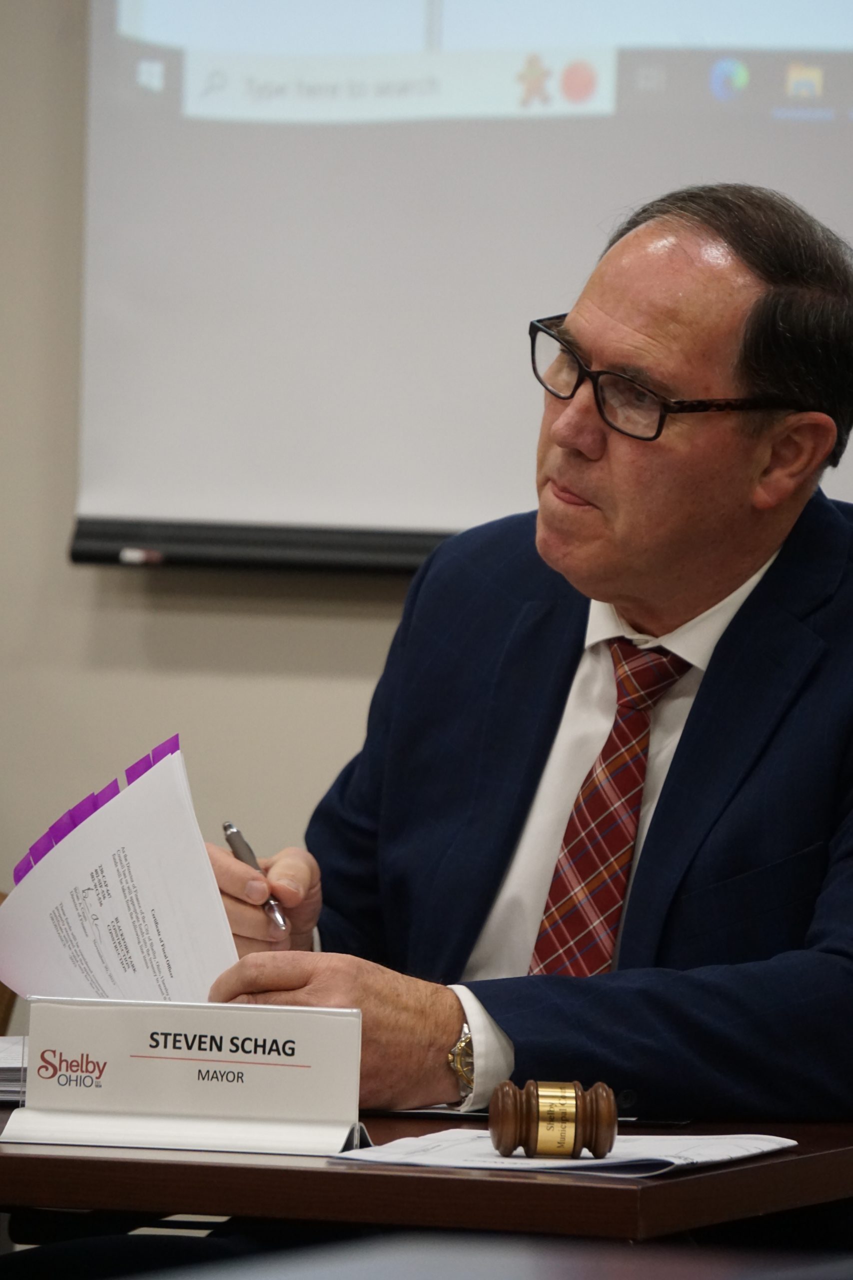 Man in black suit, red tie, and glasses.