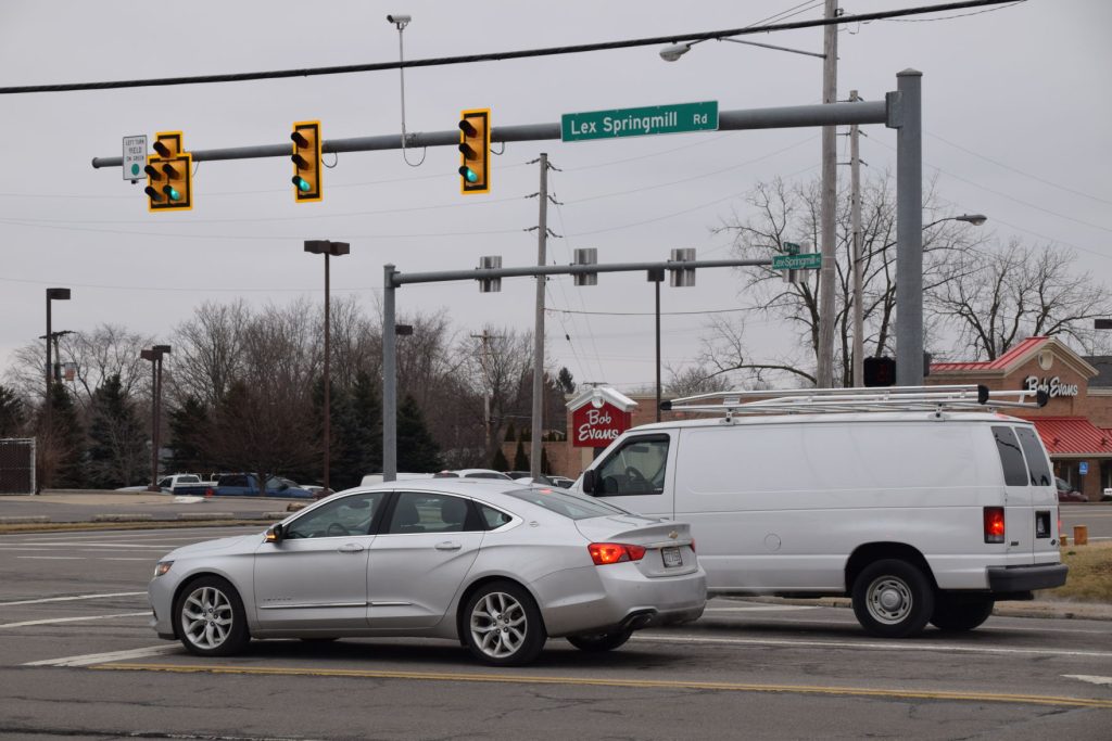 An intersection on Lexington-Springmill Road showing two cars.