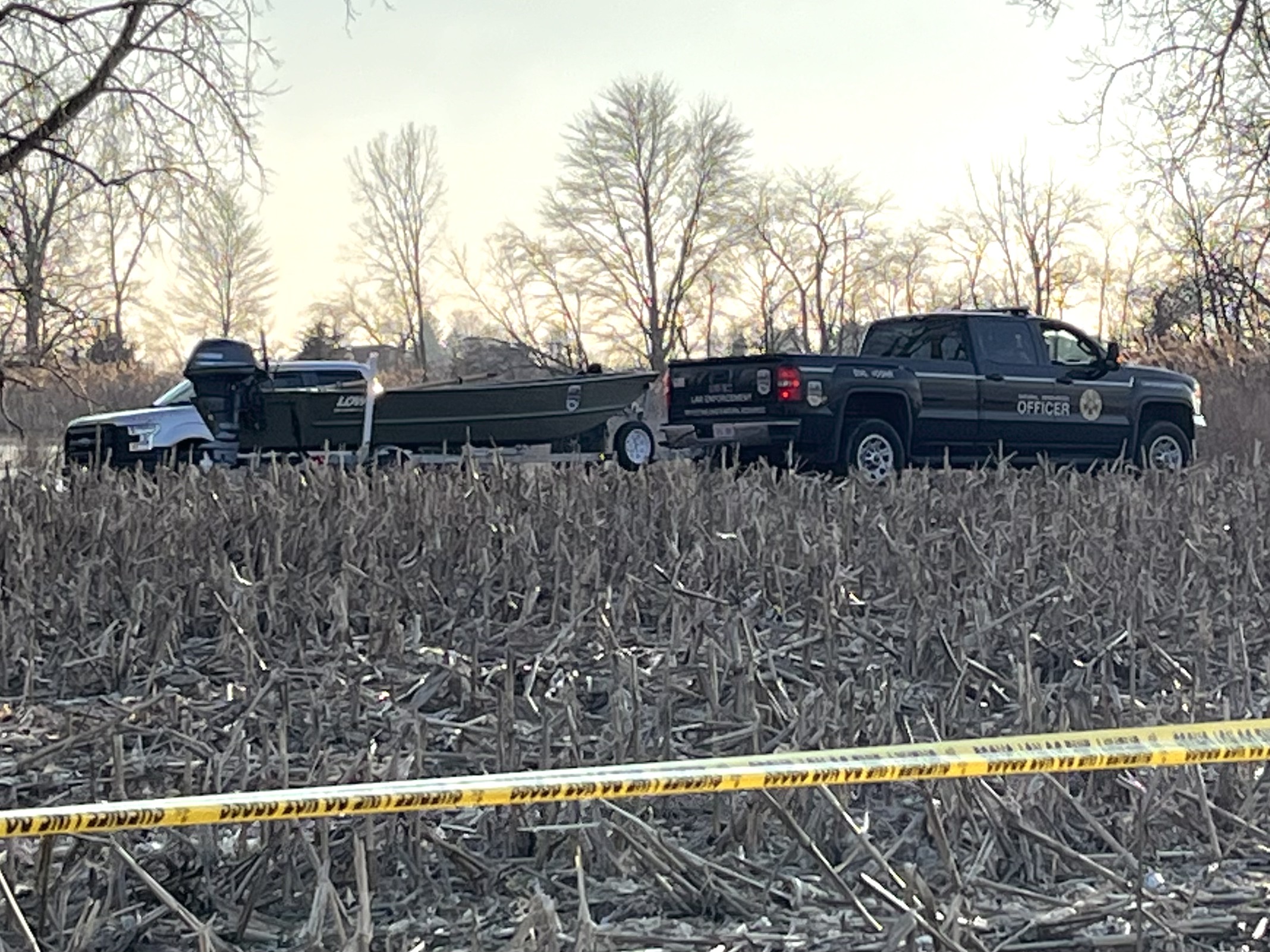 Truck with boat attached behind it in field