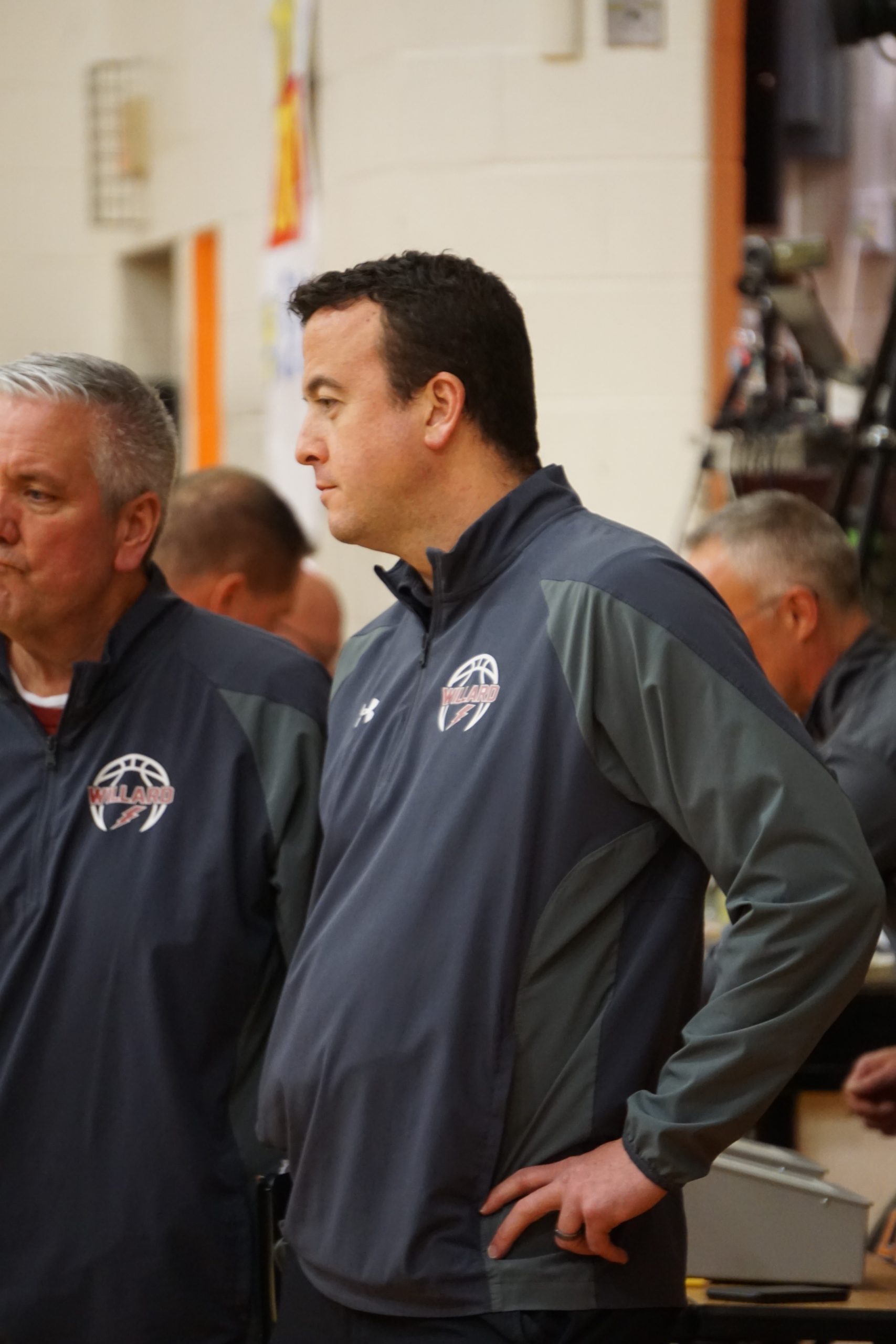Head basketball coach in gray jacket standing on sideline