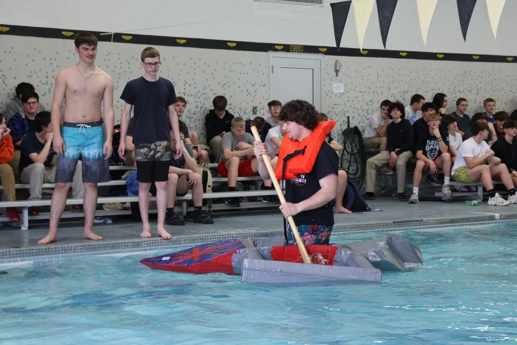 teenage boy races in Mike Cauley cardboard boat regatta at Colonel Crawford High School