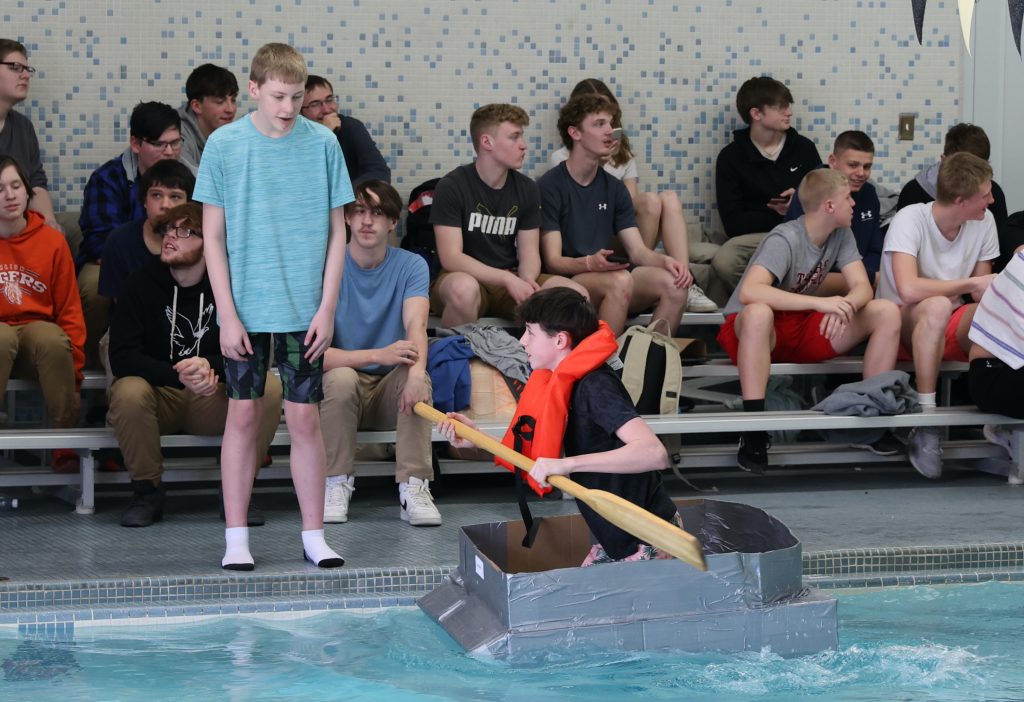 teenage boy races in Mike Cauley cardboard boat regatta at Colonel Crawford High School