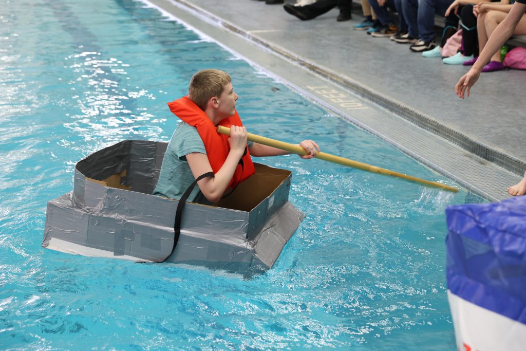 teenage boy races in Mike Cauley cardboard boat regatta at Colonel Crawford High School