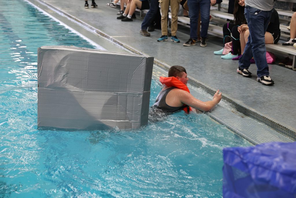 teenage boy races in Mike Cauley cardboard boat regatta at Colonel Crawford High School