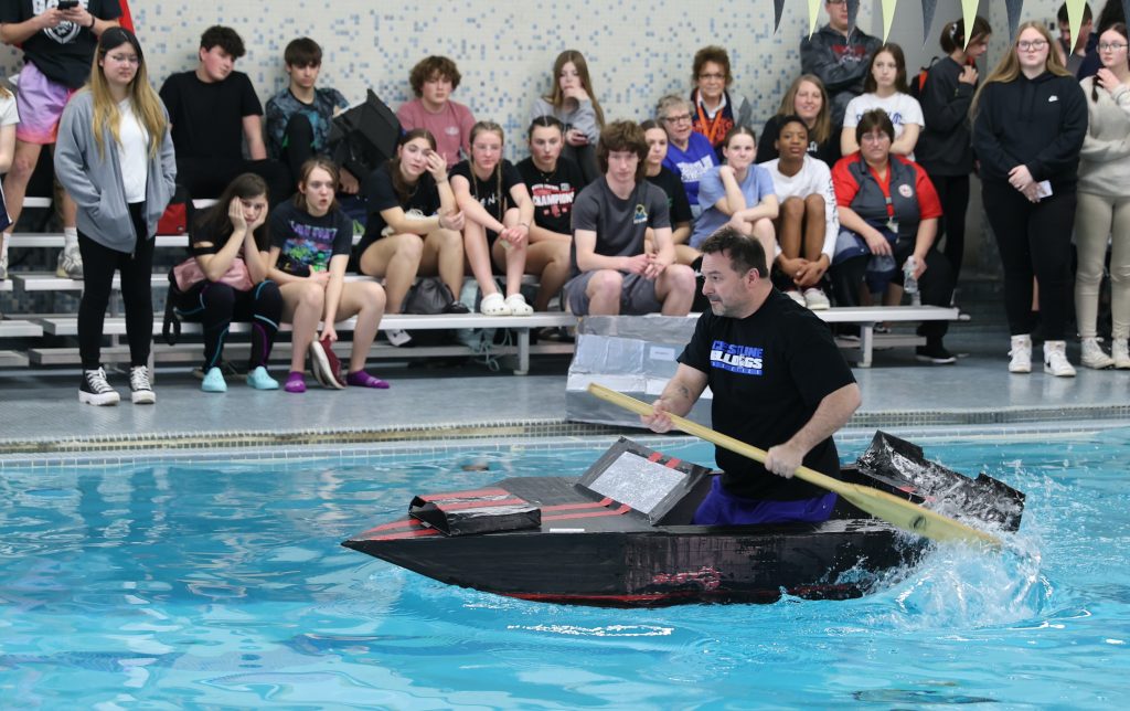 principal Jason Knight races in Mike Cauley cardboard boat regatta at Colonel Crawford High School