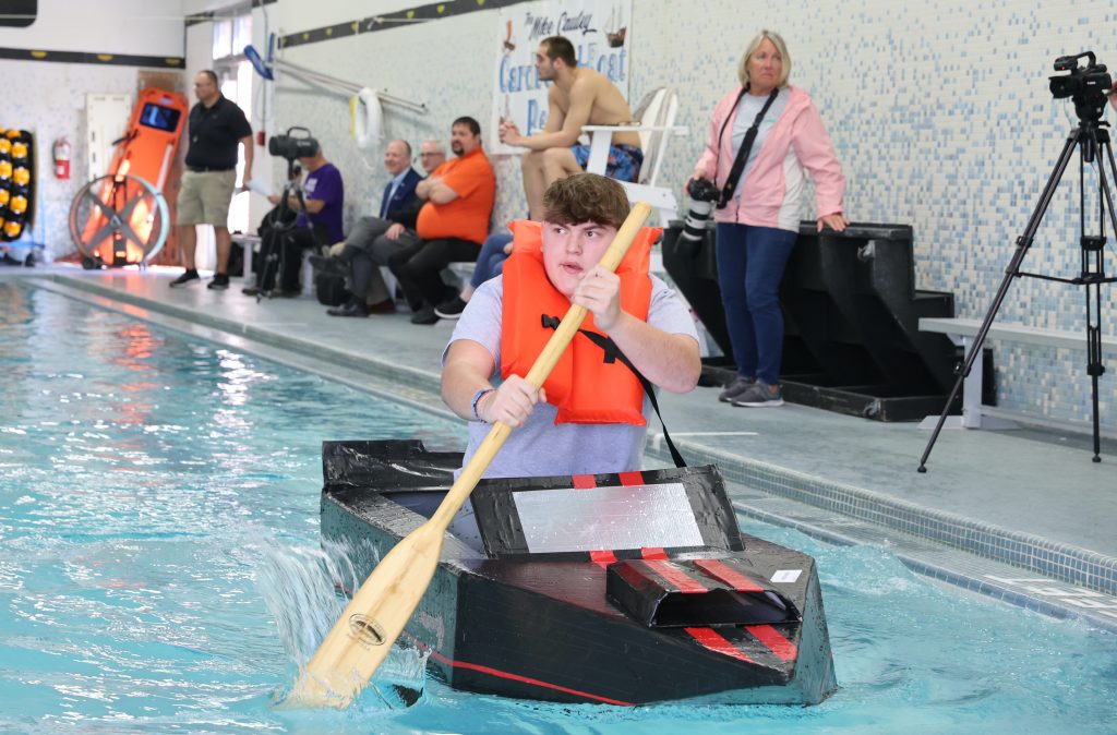teenage boy races in Mike Cauley cardboard boat regatta at Colonel Crawford High School