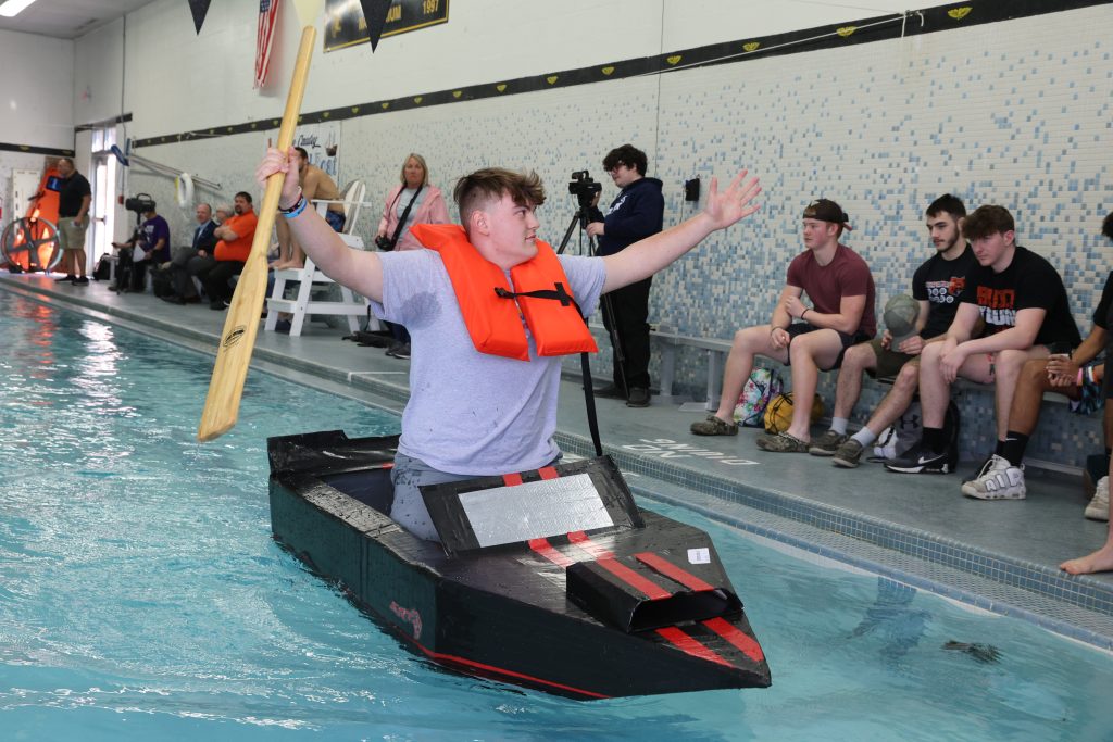 teenage boy races in Mike Cauley cardboard boat regatta at Colonel Crawford High School