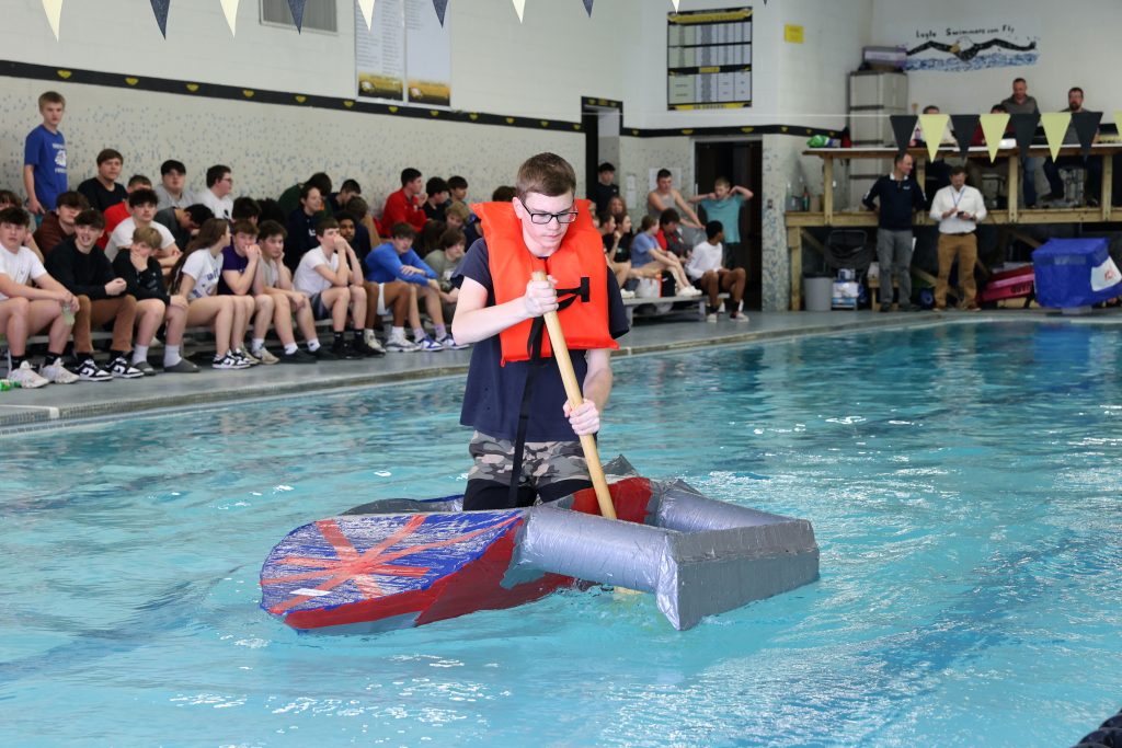 teenage boy races in Mike Cauley cardboard boat regatta at Colonel Crawford High School