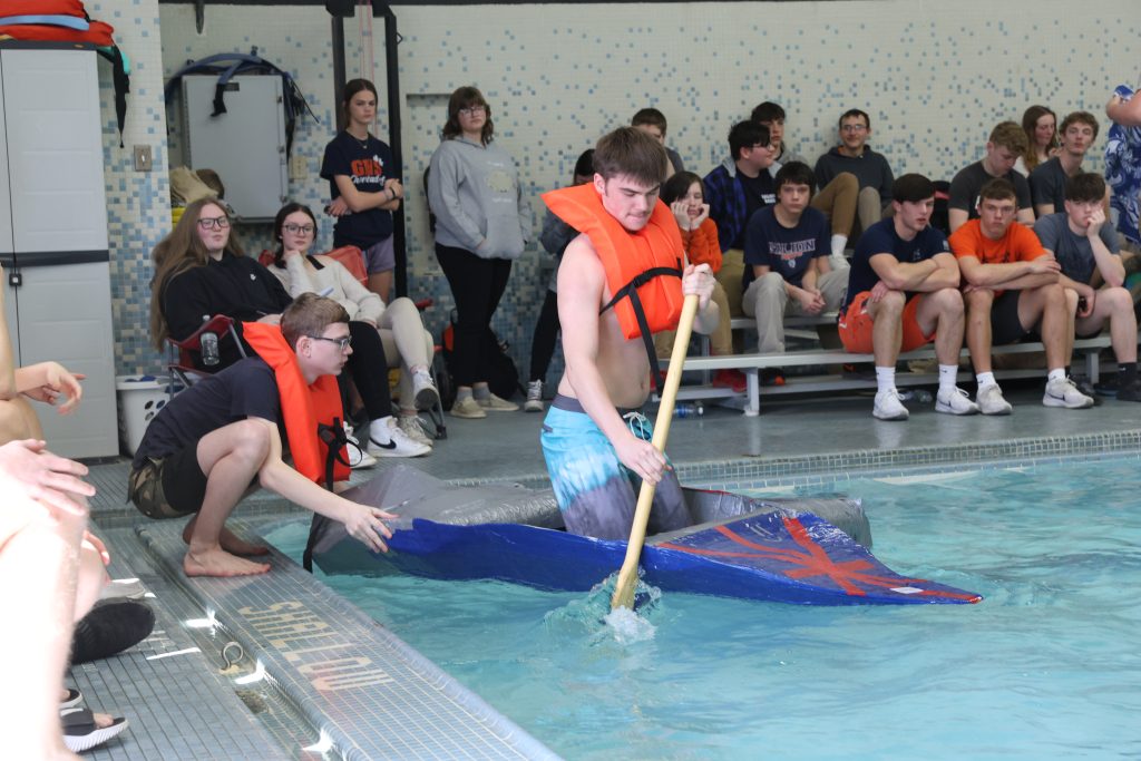teenage boy races in Mike Cauley cardboard boat regatta at Colonel Crawford High School